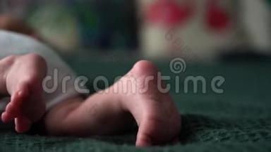 小可爱的小脚宝宝。 小新生儿`脚特写。 躺在深绿色的毯子上，穿着白色的连衣裙或连衣裙